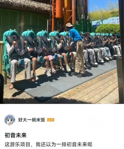 游乐园过山车项目的场景，一排乘客正坐在蓝绿色座椅上，黑色安全压肩将头部部分遮挡，姿态统一低头或捂脸，看起来像一排戴着标志性双马尾的初音未来。下方配有网友评论：'初音未来 这游乐项目，我还以为一排初音未来呢'，通过乘客与虚拟歌手发型的视觉相似性制造笑点。