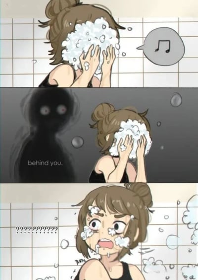 三格连环漫画描绘女生洗脸时的惊吓场景。第一格：棕色头发扎成丸子头的女生正在洗脸，双手捧着泡沫遮住脸部，旁边有音乐符号气泡，显得轻松惬意。第二格：背景突然变暗，女生身后出现一个双眼发红的黑影，下方文字显示“behind you.”，营造紧张氛围。第三格：女生惊恐地转头，脸上泡沫飞溅，眼睛瞪大，嘴巴张开，旁边满是“??????????”符号，表现出极度的震惊和害怕。