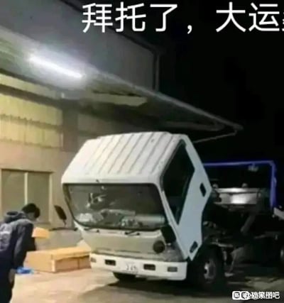 这是一张夜晚场景下的实拍静态图，画面中一辆白色轻卡的驾驶室向上翻起并倾斜，这个角度的视觉效果恰好和人弯腰拜托的姿势高度相似。图片上方配有文字“拜托了，大运”，运用了谐音梗，“大运”既可以指代大运品牌的卡车，也谐音“大运气”，以幽默的方式表达了祈求好运的诉求。画面左下角有一名穿着深色衣物的人，站在卡车旁，似乎在进行装卸或车辆维修相关的动作，背景是一栋厂房类的建筑，右下角带有“趟策图吧”的水印。