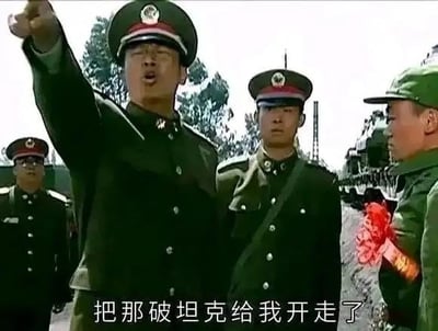 这是国产军旅剧《士兵突击》的经典名场面截图，画面中王庆瑞团长手指前方，情绪激动地大喊“把那破坦克给我开走了”，一旁戴着入伍红花的许三多神情拘谨茫然。该截图常被制作成表情包，用于表达不耐烦地驱赶、嫌弃某个人或事物的情绪，图中没有双关、谐音梗或暗示内容。