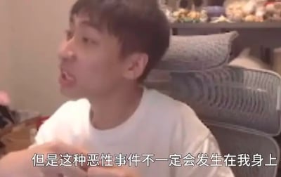 图中是一位男性主播坐在电竞椅上，表情夸张、嘴巴大张，正处于激动发言的状态，画面下方配有字幕“但是这种恶性事件不一定会发生在我身上”。背景是室内直播环境，能看到一些摆放的小物件，整体场景是主播在直播过程中表达自身对风险事件的看法。