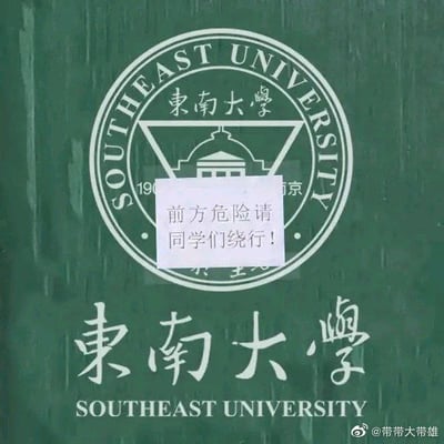 图片展示东南大学校徽和校名，中间被贴了一张纸条，上写“前方危险请同学们继续行！”。这种提示与常规安全提示相反，带有浓厚的反讽和自嘲意味。多被用来表达明知前方有困难、挑战却还不得不硬着头皮上的无奈、幽默心态，是高校、学生圈常见的自黑梗图。文字恶搞了常见的“前方危险 请止步”语句，效果夸张而搞笑。