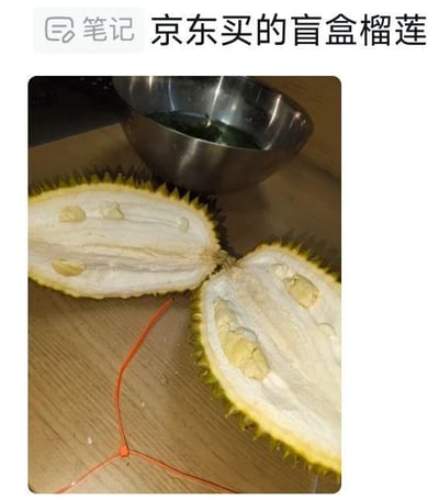 这是一张用户开箱京东购买的盲盒榴莲的实拍图，被掰开的榴莲内部大部分是白色的果壳部分，只有零星几小块体积很小的榴莲果肉，呈现出明显的果肉量不足的状态，直观展现了这次盲盒榴莲购物的糟糕体验，大概率是用户用来吐槽这次购物踩雷的实拍记录。