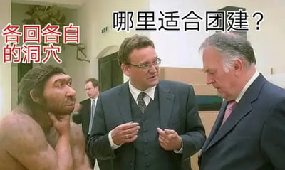 这是一张搞笑的合成梗图，画面呈现了室内场景，两位穿着正式西装的职场人士正在交流讨论，其中一位提出问题“哪里适合团建？”，旁边被P进来的原始人则一脸无奈地托着下巴，给出“各回各自的洞穴”的回答。这个回答用原始人的生活场景来隐喻当代打工人不想参与团建，更希望拥有私人空间、各自休息的真实心态，通过原始人与职场场景的反差感，精准戳中职场人对团建的抵触情绪，制造出幽默搞笑的效果，引发职场群体的共鸣。背景中还有一位穿着西装的男士，进一步烘托出职场的氛围。
