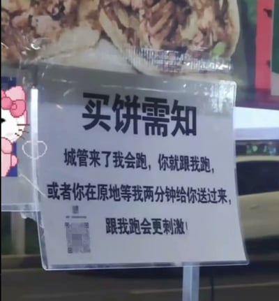 这是一张实拍的街边流动饼摊提示牌照片，主体是被透明塑封的白色提示牌，上方写有标题“买饼须知”，下方内容用调侃的语气告知顾客，如果遇到城管巡查摊主会离开，顾客可以选择跟着摊主一起跑，或者在原地等待两分钟摊主会把饼送回来，还打趣称“跟我跑会更刺激”，提示牌左下角还有被模糊处理的二维码。背景可以看到摊位摆放的饼类食物样品，侧边还有Hello Kitty的卡通装饰贴纸，整体内容幽默体现了流动摊贩的经营特点，话术非常接地气。