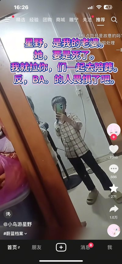 这是一张抖音竖屏视频截图，画面中一名男生对着镜子用手机自拍，旁边还有一位人物的部分身影。画面上叠加了大段故意乱加标点的中二文字：“星野，是我的老婆。她，要是死了。我就拉你，们一起去陪葬。反，BA。的人畏惧了吧。”，右上角还有观众评论“这标点符号是故意的吗？”“等我回国处理”。这是《蔚蓝档案》的粉丝整活内容，将游戏角色星野称作“老婆”，用过激的威胁发言搭配错误的标点断句，制造出滑稽搞笑的中二效果。
特别说明：图中的标点符号是故意乱加的，属于玩梗手法，让原本严肃的威胁发言变得荒诞搞笑。