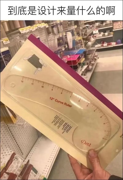 图片拍摄于商超的手工用品售卖区，一只手拿着仍处于原包装内的Dritz品牌12英寸曲线尺，这款尺子本是服装打版时用来测量、绘制领口、袖窿等弧形部位的专业工具，但其整体弯曲的轮廓外形极易让人联想到男性生殖器官，图片顶部搭配文字“到底是设计来量什么的啊”，放大了这种视觉歧义，营造出搞笑的玩梗效果。