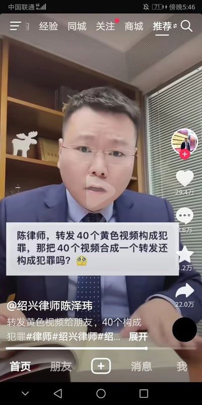 这是一张抖音平台的视频截图，画面主体是身着西装、佩戴眼镜的绍兴律师陈泽玮，他身处带有书架、小鹿摆件与百叶窗的办公室场景中，正准备解答网友的法律疑问。画面中间弹出网友的提问：“陈律师，转发40个黄色视频构成犯罪，那把40个视频合成一个转发还构成犯罪吗？”，视频左下角标注了博主账号@绍兴律师陈泽玮，下方显示视频的部分文案“转发黄色视频给朋友，40个构成犯罪#律师#绍兴律师#绍...”，右侧栏展示了该视频的互动数据：29.4万点赞、3.6万评论、1.2万收藏、22.0万转发。