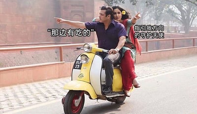 这是一张经过文字加注的趣味梗图，画面截取了影视片段中的场景：一男一女骑着一辆黄白配色的复古踏板摩托车行驶在户外道路上，驾驶位的男子身体侧转，伸手指向画面左侧，配文“那边有吃的”；后座的女子同样伸手指向同一方向，配文“指引我方向的守护天使”。两人的表情都带着急切与兴奋，结合配文，用幽默的方式调侃了吃货群体对于美食的执着，将指向食物的人戏称为“守护天使”，充满了生活化的趣味。