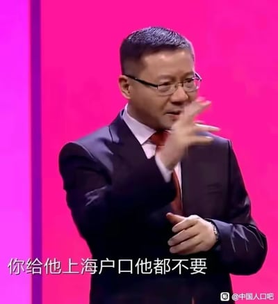这是一段公开演讲的视频截图，画面中的人物是学者张维为，他身着深色西装、内搭白衬衫并系着红领带，佩戴眼镜，正抬手做出演讲的手势，面部表情严肃认真，似乎在阐述某个观点。画面下方配有白色的字幕文字“你给他上海户口他都不要”，这句话是其演讲内容的一部分，意在表达当下部分人群对上海户口的态度发生转变，不再将其视为极具吸引力的资源，该内容常被用来引发关于城市吸引力、户口价值、人口流动等相关话题的讨论。
