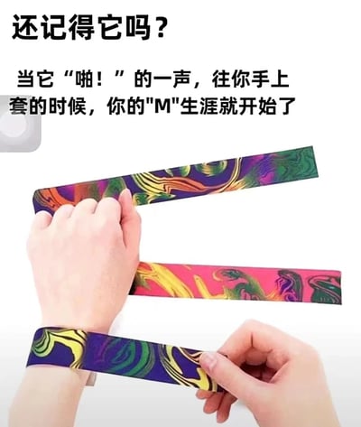 图片展示了一只手正在将彩色啪嗒手环往另一只手腕上套的场景。手环具有鲜艳的彩色漩涡图案，主要以紫色、绿色、黄色和粉色为主。图片上方配有文字："还记得它吗？当它'啪！'的一声，往你手上套的时候，你的'M'生涯就开始了"。这里的'M'是双关语，既指手环套在手腕上形成的形状，又在网络用语中暗示受虐倾向，制造幽默效果。