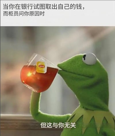 图片上方配有文字“当你在银行试图取出自己的钱，而柜员问你原因时”，下方主体画面是卡通角色科米特青蛙（绿色玩偶形象）正手持一杯泡有立顿茶包的红茶，低头饮用，杯中的红茶呈现出温暖的橙红色。画面底部配有文字“但这与你无关”，通过科米特淡定喝茶的神态与文字结合，幽默地表达了面对银行柜员询问取钱原因时的无奈与“这是个人隐私与你无关”的态度。