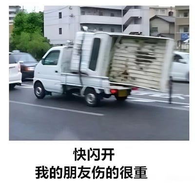 图片中一辆白色小型卡车正在城市道路上行驶，车尾货厢敞开，里面堆放着木板。背景可见多层建筑和其他车辆。图片下方配有中文文字：‘快闪开 我的朋友伤的很重’。通过将紧急的文字内容与普通的木板货物形成反差，制造出幽默搞笑的效果。