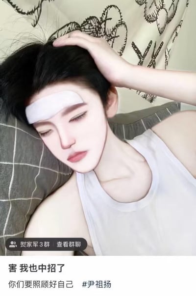 这是一张竖屏的社交媒体动态截图，图中人物尹祖扬额间贴着白色退热贴，单手扶头靠在格子枕头上，面部经过AI或修图处理成精致的漫画风格，看起来虚弱疲惫，呈现出生病的状态。截图下方配文：“害 我也中招了 你们要照顾好自己 #尹祖扬”，左下角还有“熨家军3群 查看群聊”的标识，是尹祖扬在粉丝相关的社交动态里，告知粉丝自己生病“中招”，同时暖心提醒粉丝注意照顾好自己。