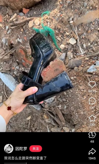 画面中一只手拿着一双黑色高跟鞋，鞋底被塞进了一块红砖，环境是建筑垃圾堆，画面带有极强的违和和幽默感。旁边配文：“我说怎么走路突然脚变重了”，结合实际，显然是一双鞋在土堆中“进化”成了“砖鞋”，制造了视觉和现实的夸张反差，引发网友的共鸣和笑点。这种场景多见于调侃、吐槽生活“倒霉事”或“囧事”，属于生活幽默。同画面配文之间形成了明显的双关和谐音梗含义，即“脚变砖（重）了”、“砖鞋”。