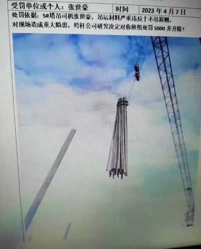 图片为一张处罚通知截图，上方为文字说明区域，详细列出受罚人为5#塔吊司机张世豪，处罚时间为2023年4月7日，原因是其在吊运材料时严重违反“十不吊”原则，对现场造成重大安全隐患，均杆公司决定对其班组处以5000元罚款并予以开除。下方配有一张现场照片，展示了一台塔吊在蓝天白云背景下吊运长条形材料的场景，塔吊结构和吊索清晰可见。