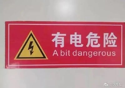 这是一块红色的安全警示标识，左侧配有黄色的高压危险三角警示图标，上方是中文警示语“有电危险”，但下方对应的英文翻译却错误地写成了“A bit dangerous”，将原本严肃的高压危险警示，错误翻译成了程度轻微的“有点危险”，形成了强烈的反差感，十分搞笑。