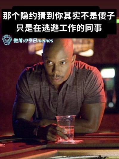 图片中是一位肌肉发达的光头男性，他穿着深色短袖衬衫，单手撑在桌面上，手中握着一个透明塑料杯，身体前倾，眼神锐利且带着怀疑的表情看向一侧。图片上方有黑色背景白色文字：“那个隐约猜到你其实不是傻子 只是在逃避工作的同事”，幽默地描绘了职场中同事看穿他人摸鱼行为的场景。