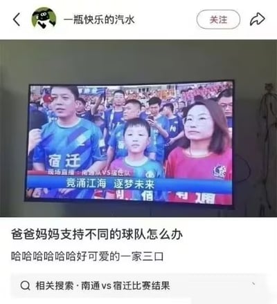 该图是中文社交平台的内容截图，上层是用户拍摄的电视播放足球赛事的画面，内容为南通队对阵宿迁队的赛事直播观众席镜头：一家三口共同观赛，父亲身着印有“宿迁”字样的蓝色球衣支持宿迁队，母亲身着红色球衣支持南通队，二人中间的孩子穿着蓝紫渐变球衣，画面下方配有赛事宣传语“竞涌江海 逐梦未来”；截图下方是发布者的配文，调侃父母支持不同球队的情况，同时夸赞一家三口很可爱，底部还有相关搜索入口“南通vs宿迁比赛结果”，整体内容充满趣味，展现了家庭中成员支持不同主队的可爱反差。