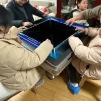 这张照片呈现了一个有趣的视觉错位场景：四位普通人围坐在一张桌子旁，做出打麻将的动作，但从拍摄角度看，桌面仿佛不存在，像是在对着空气打牌。实际上是桌子的特殊结构或拍摄角度造成的错觉，画面充满生活趣味，展现了家庭聚会时的欢乐瞬间，让人感受到生活里的小惊喜。