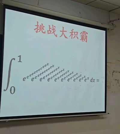这是一张实拍的教室投影幕布画面，幕布顶部用红色字体写着“挑战大积霸”，是谐音“大恶霸”的玩梗表述；下方展示了一道高等数学的定积分题目，积分区间为0到1，被积函数是层数非常多的嵌套指数函数，从最内层的e^x向外反复叠加e的指数，结构极其复杂，整体是调侃高数积分题型难度过高的搞笑梗图。