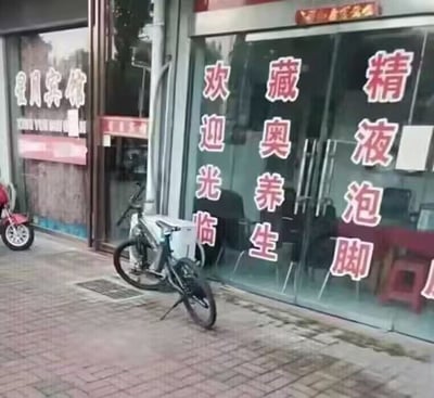 这是一张拍摄街边店铺的照片，店铺玻璃门上贴着竖排的红色标语，从右到左正确的竖排读法应为“精品泡脚”“藏奥养生”“欢迎光临”，但由于竖排文字的排版，若错误地以横向从左到右读取，会读出“精液泡脚”的尴尬内容，制造出荒诞搞笑的反差效果。
这是利用竖排文字的排版歧义形成的误读梗，属于视觉误导类的搞笑内容。