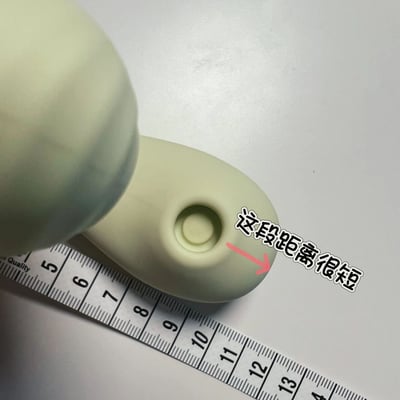 图片展示了一个浅绿色、表面光滑的物体（可能是玩具或小型器具部件）的特写，放置在白色背景上。物体下方有一把标有5-13厘米刻度的尺子，用于测量其尺寸。物体侧面有一个圆形孔洞，旁边用红色箭头指向该孔洞，并配有手写风格的文字“这段距离很短”，提示该孔洞相关的距离（如深度或直径）较短。整体画面清晰，聚焦于物体细节和测量场景。