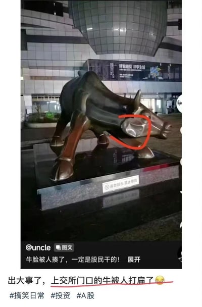 这是一张社交媒体发布的实拍梗图，内容为上海证券交易所门口象征牛市的铜牛雕塑，其脸部（红圈标注位置）被砸至凹陷变形。图中配文调侃“牛脸被人揍了，一定是股民干的！”“出大事了，上交所门口的牛被人打扁了😅”，雕塑底座还有“请勿敲击 禁止攀爬”的提示牌。该梗用铜牛被打暗喻A股表现不佳，将股民对股市行情的不满以搞笑吐槽的方式呈现，引发股民群体共鸣。