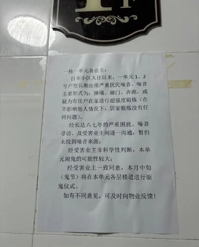 图片中展示了一张张贴在瓷砖墙面上的纸质通知，上方有一个黑色底金色花纹及字母的标牌。通知内容显示，某小区一栋一单元的业主因长期受不明噪音（捶墙、砸门、奔跑等）困扰达六七年，在无法找到噪音来源后，经业主非科学性判断认为“闹鬼可能性较大”，遂一致同意于本月中旬（鬼节）在单元各层楼道进行驱鬼仪式，并注明如有不同意见可向物业反馈。整个场景呈现出一种因长期生活困扰而产生的荒诞又无奈的社区生活片段。