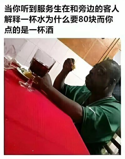 图片上方有文字‘当你听到服务生在和旁边的客人解释一杯水为什么要80块而你点的是一杯酒’，下方是一张真实照片，一名穿着绿色上衣的男子坐在铺有红色桌布的餐桌前，左手拿着一块食物，右手扶着一杯深色液体（疑似红酒），头部向上抬起，表情看起来惊讶又带着一丝担忧，似乎刚听到昂贵的水费价格后联想到自己点的酒可能价格不菲。