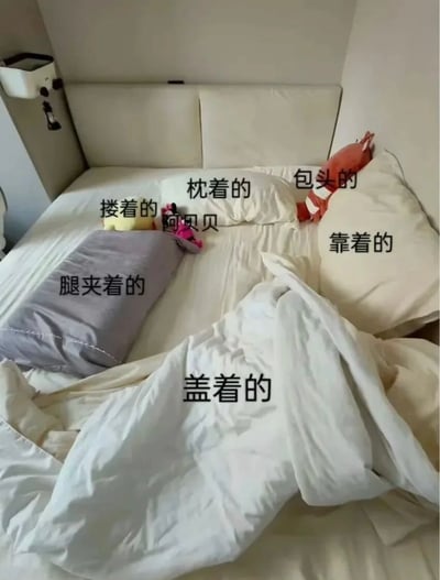 凌乱又温馨的单人床大公开！床上堆满了睡觉时‘各司其职’的宝贝：左边有腿夹着的灰色长抱枕，中间是搂着的粉色‘阿贝贝’玩偶和黄色小玩具，右边靠着的白色枕头旁还有个包头的红色条纹玩偶，当然少不了身上盖着的白色被子～每个物品都有专属‘睡觉姿势’，简直是独居人的睡眠安全感图鉴！