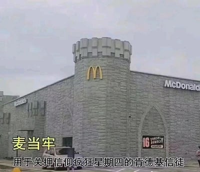 这是一张结合谐音梗与网络热梗的搞笑图片，主体是外观设计为城堡/监狱风格的麦当劳门店，建筑采用灰色石质外墙，搭配塔楼结构，塔楼正面有麦当劳的金色M标志，建筑左右墙面印有“McDonald's”英文标识。图片下方配有中文趣味文字，将“麦当劳”谐音为“麦当牢”，并注释“用于关押信仰疯狂星期四的肯德基信徒”，结合肯德基“疯狂星期四”的热门网络梗，制造出两大快餐品牌爱好者群体“对立”的搞笑设定，通过反差感和玩梗来制造趣味效果，属于快餐品牌相关的网络迷因内容。