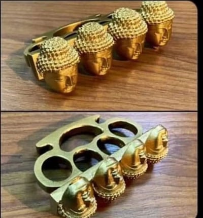 图片分为上下两部分，均展示同一金色物体。上半部分显示四个佛头并排排列，佛头有典型的螺发和面部特征；下半部分揭示该物体实际是一个指虎（brass knuckles），佛头下方连接着带手指孔的金属结构，将宗教神圣意象与暴力武器元素结合，形成强烈的视觉反差和荒诞感。