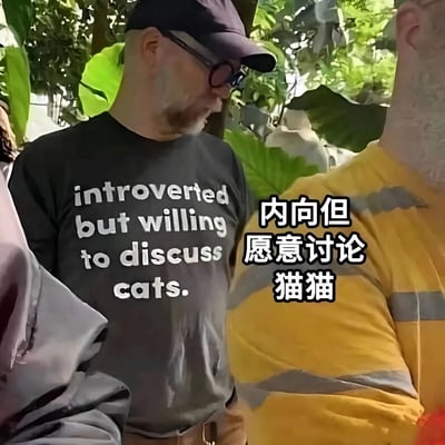 图中一位戴着紫色帽子和眼镜的男子穿着印有英文标语'introverted but willing to discuss cats'的黑色T恤，右侧配有中文翻译'内向但愿意讨论猫猫'。背景是茂密的绿色树叶，男子身旁还有穿着黄色条纹上衣的其他人，整体场景像是在户外或植物园中，通过服装文字幽默展现内向者对猫咪话题的特殊开放态度。