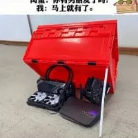 这是一张带有文字加注的原创拍摄梗图，画面中一个红色大箱子斜靠在地面，箱子前方摆放着无人机、笔记本电脑、带天线的路由器等电子设备。图上方配有对话文字：“闺蜜：你男朋友发了😡 我：马上就有了😎”。图中玩了谐音梗，利用“箱”与“香”的谐音，将电子设备放在箱子下方，假装是“开箱（香）”的内容，以此回应闺蜜的话，搞笑又机智，调侃了情侣间的互动日常。