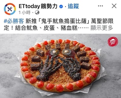 这是必胜客推出的万圣节限定款「鬼手鱿鱼捣蛋比萨」，披萨以暗黑搞怪的造型贴合万圣节氛围：底部铺有类似碎料的基底，中间用处理成黑色的鱿鱼做成鬼手的视觉效果，搭配切开的皮蛋、块状猪血糕，披萨边缘环绕着红色的圆形配料，整体视觉猎奇吸睛。这张图是ETtoday饿势力在社交平台发布的新品宣传内容，旨在推广这款结合在地特色食材的节日限定披萨。