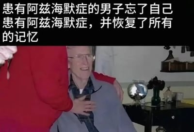图片展示了一位戴着眼镜的老年男性坐在椅子上，面带微笑，被一位穿红色衣服的人从身后拥抱。老人表情温暖，似乎处于感动或幸福的情绪中。图片上方有文字说明：'患有阿兹海默症的男子忘了自己患有阿兹海默症，并恢复了所有的记忆'。背景中可以看到室内陈设，包括一个地球仪和一些装饰品，营造出温馨的家庭氛围。