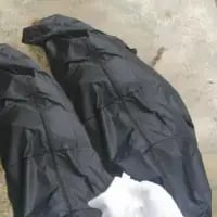 这是一张利用视觉错位效果拍摄的照片，黑色的布袋铺在平面上，袋口露出的白色区域和布袋的褶皱组合在一起，看起来仿佛是一个被装入袋中的人，制造出逼真的视觉错觉，让人第一眼产生误解，颇具趣味。