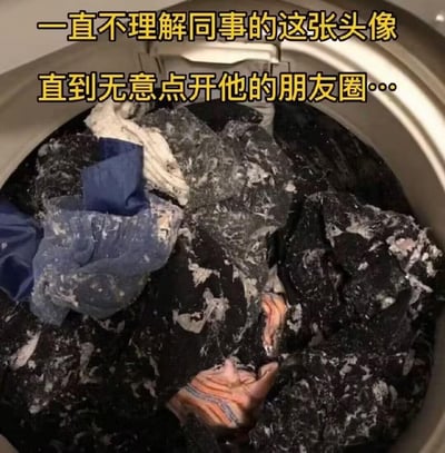 这张图展示了洗衣机内部的狼藉场景：深色衣物与其他颜色衣物混洗后，沾满了大量白色絮状物，看起来像是洗衣失败的现场。配文「一直不理解同事的这张头像，直到无意点开他的朋友圈…」，揭晓了这张图作为同事头像的原因——这就是他真实的洗衣日常，充满了生活里的搞笑乌龙，让人哭笑不得。