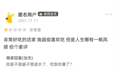 截图展示了美团平台上一条有趣的用户评价互动。匿名用户（美团会员）在2021年11月11日给一家认为“非常好吃”且“超级喜欢”的店家打了1星“非常差”的评价，理由竟是“人生哪有一帆风顺”。店家当天愤怒回复：“你是不是脑子里进水了，吃饭吃傻了？”，形成强烈反差的搞笑对话场景。