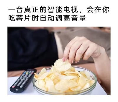 图片上方配有文字“一台真正的智能电视，会在你吃薯片时自动调高音量”，下方是一张实拍图：一只手正从玻璃碗中拿起一片薯片，碗旁放着一个电视遥控器。整体通过幽默的文字结合生活化场景，调侃智能电视若能根据用户吃薯片（发出声响）自动调高音量以抵消噪音，会是“真正智能”的体现，展现了对智能设备功能的趣味想象。