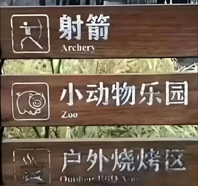 图片展示了一块垂直排列的木质指示牌，分为三个水平区域。每个区域上方都有白色图标，下方配有中英文对照文字。最上方区域图标为一个人形拉弓的简笔画，文字为“射箭 Archery”；中间区域图标是一只卡通小猪，文字为“小动物乐园 Zoo”；最下方区域图标为一个带火焰的烧烤架，文字为“户外烧烤区 Outdoor BBQ Area”。背景隐约可见绿色植物，推测为户外休闲场所的设施指示牌。