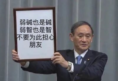 这是一张经过P图改编的静态图文混排图，图中一位身着深色西装、系着蓝色领带的男士双手举着一块带有棕色边框的白色牌子，牌子上印有黑色文字：“弱碱也是碱，弱智也是智，不要为此担心朋友”。这张图利用“弱碱”与“弱智”的谐音关系，将化学概念里的弱碱和调侃性的表述进行关联，以一种幽默、调侃的语气来安慰他人，整体风格搞笑诙谐，属于网络上常见的玩梗类创作图。