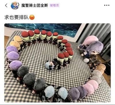这是一张社交媒体截图，显示了一个名为“魔警骑士团全斯”的管理员在群聊中发布的内容。上方文字为“求也要排队 😠”，下方配图是一张桌子上摆放着许多毛绒玩具，这些玩具被整齐地排列成一个圆形，有红色、黄色、紫色等不同颜色的头部，右侧还有一个较大的紫色头发毛绒玩偶。整体呈现出一种幽默调侃的氛围，用毛绒玩具排队的场景呼应“求也要排队”的文字内容。