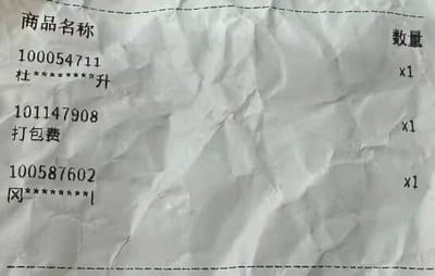 这是一张褶皱的购物小票翻拍图，小票以“商品名称-数量”的格式记录了三项消费内容：编号为100054711、名称打码为“杜********升”的商品1件，编号为101147908的打包费1份，以及编号为100587602、名称打码为“冈********|”的商品1件。小票纸张有明显褶皱，部分商品名称做了模糊打码处理，整体是常见的消费凭证样式。