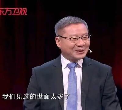 这是一张东方卫视节目《这就是中国》的视频截图，图中人物为学者张维为，他身着深色西装、白色衬衫搭配蓝色领带，佩戴眼镜和耳麦，面带微笑，正处于节目发言的场景中。画面下方配有字幕“我们见过的世面太多了”，这句话原本是节目中的发言内容，后来被网友截取作为梗图，常用来表达见多识广、对各类事物习以为常的态度，也可用于调侃或回应一些让人觉得见怪不怪的事情。