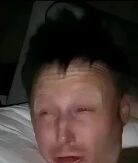 图片中是一个表情夸张的男性，头发凌乱，眼睛半睁，嘴巴微张，似乎刚睡醒或处于迷茫状态，背景看起来像是在床上。男子面部表情显得有些困惑和疲惫，整体给人一种刚睡醒还没完全清醒的感觉。