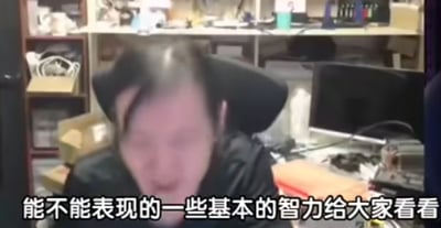图片显示一个人坐在电脑前的办公环境中，面部被模糊处理。图片下方有文字：'能不能表现的一些基本的智力给大家看看'，看起来像是在吐槽或调侃画面中的人。背景中可以看到办公桌上的各种物品和电脑设备。