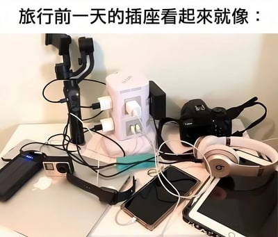一张展示旅行前一天充电场景的照片，画面中一个白色插线板上插满了各种充电器，周围散落着多部手机、平板电脑、相机、耳机、充电宝和智能手表等电子设备，充电线杂乱交错，生动展现了现代人旅行前集中充电的混乱状态。