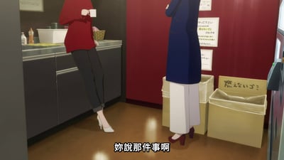 动画场景中，两位女性角色在厨房环境中对话。左侧角色穿着红色上衣和黑色裤子，脚踩白色高跟鞋，单手拿着白色杯子倚在灰色厨房台面上；右侧角色穿着蓝色长款外套和白色长裤，脚踩红色高跟鞋，双臂交叉站立在几个纸箱旁。背景是红色墙壁，上面贴有白色纸张，地面为棕色木地板。画面底部有中文字幕“妳說那件事啊”。